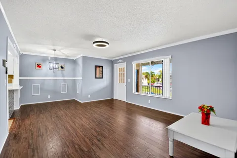 a view of an empty room with window and wooden floor