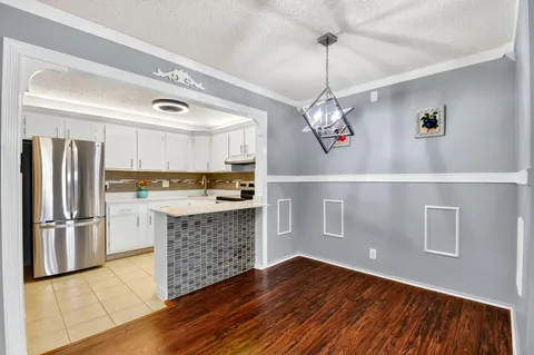a kitchen with a refrigerator and a wooden floor