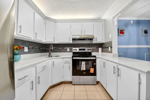 a kitchen with stainless steel appliances granite countertop a stove and white cabinets