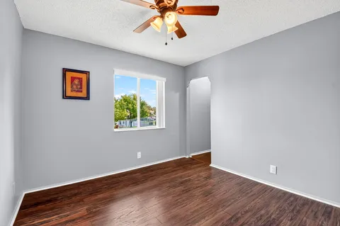 a view of an empty room with window and wooden floor