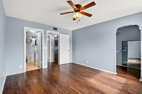 an empty room with wooden floor and a ceiling fan