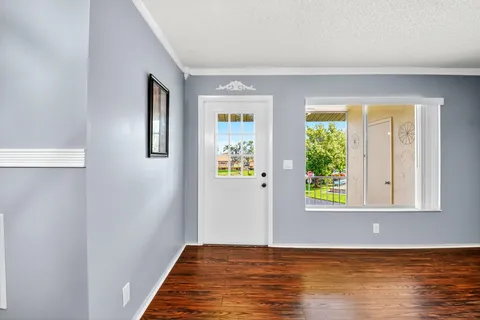 a view of an empty room with window and wooden floor