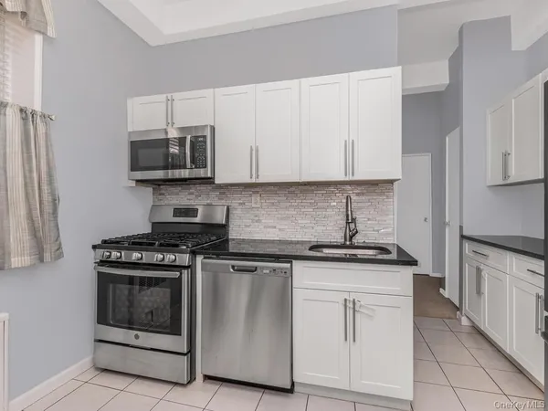a kitchen with white cabinets and appliances