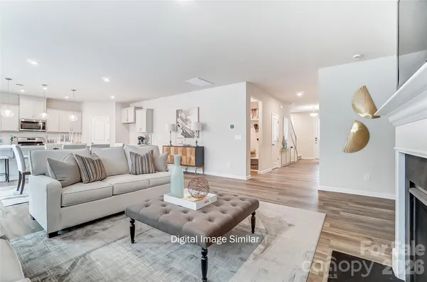 a living room with furniture kitchen view and a wooden floor