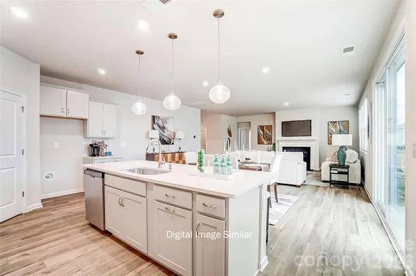 a kitchen with a sink a stove a refrigerator and white cabinets with wooden floor