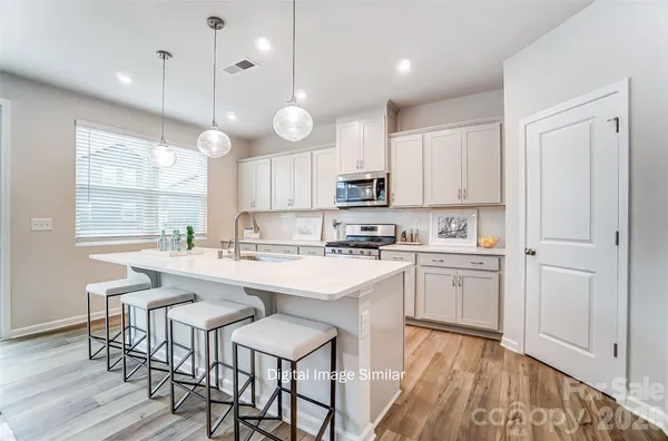 a kitchen with kitchen island granite countertop a sink cabinets and wooden floor