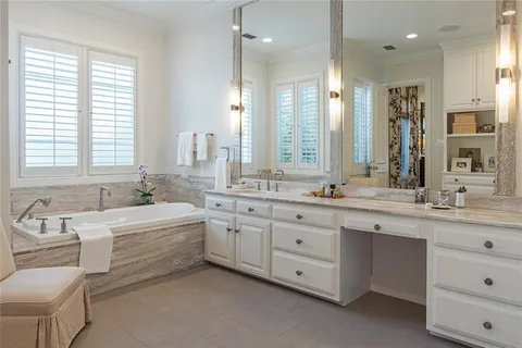 a bathroom with a double vanity sink a large mirror and a bathtub