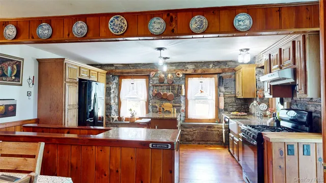 a view of a kitchen with stainless steel appliances wooden floor and a refrigerator