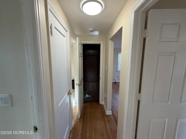 a view of a hallway with wooden floor and closet area