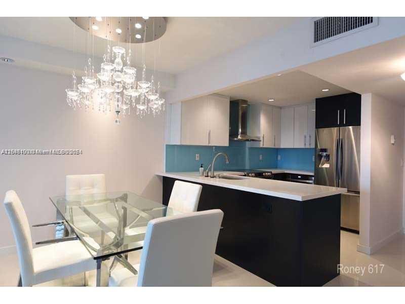2301 Collins Avenue, Unit 617 Miami Beach, FL 33139 - Photo 3 of 8 a kitchen with stainless steel appliances kitchen island a chandelier in it