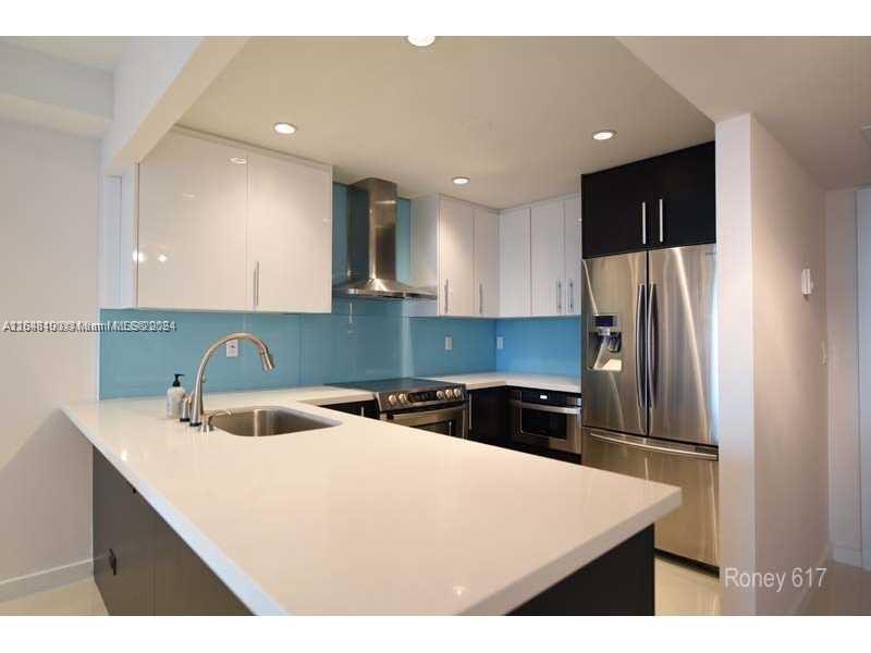 2301 Collins Avenue, Unit 617 Miami Beach, FL 33139 - Photo 4 of 8 a kitchen with a sink a refrigerator and cabinets