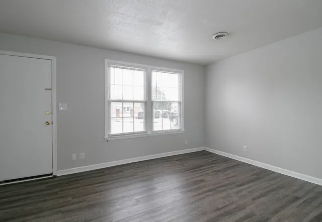 an empty room with wooden floor and windows