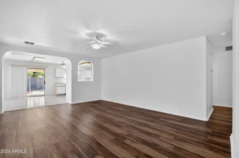 an empty room with wooden floor fan and windows