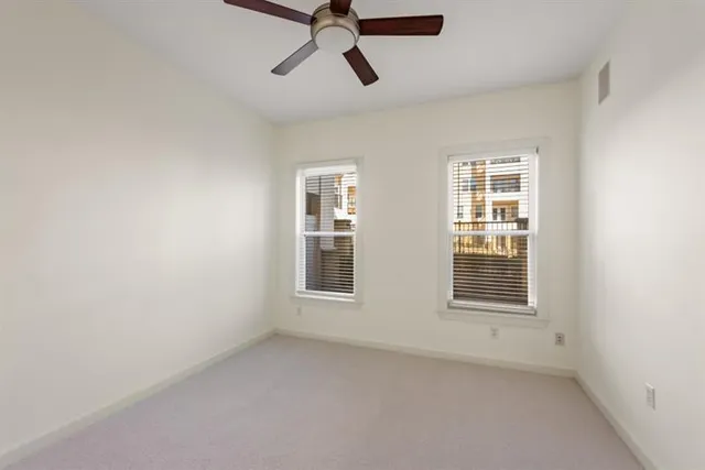 an empty room with windows and fan