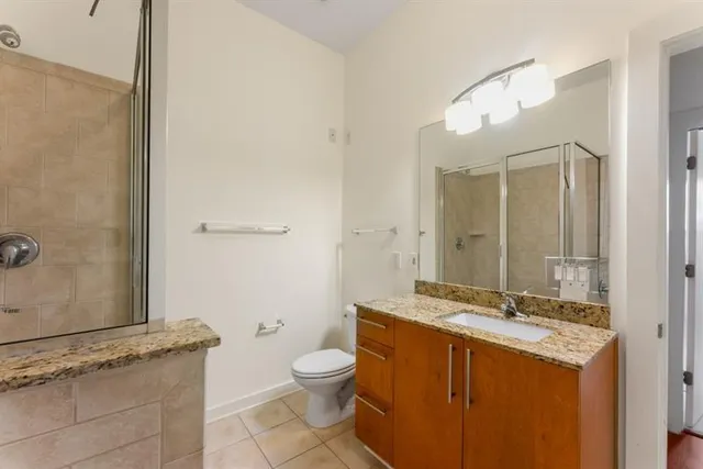 a bathroom with a granite countertop sink a mirror and a toilet
