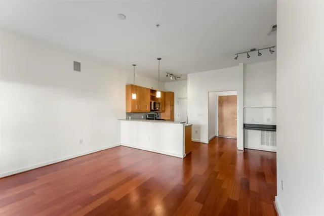 a view of a hallway with wooden floor and a refrigerator