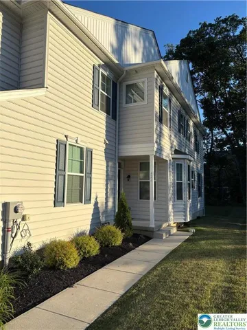 a view of a white house with a yard and plants