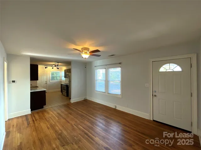 a view of an empty room with window and wooden floor