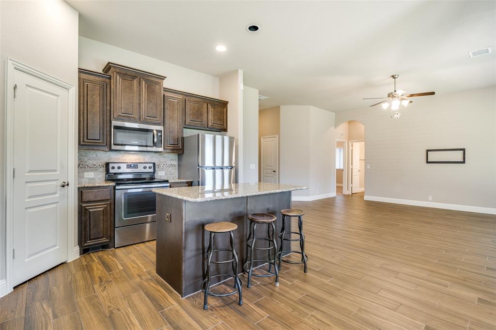 556 Avery Pointe Lavon, TX 75166 - Photo 9 of 32 a kitchen with stainless steel appliances granite countertop a stove top oven a sink dishwasher a dining table and chairs with wooden floor