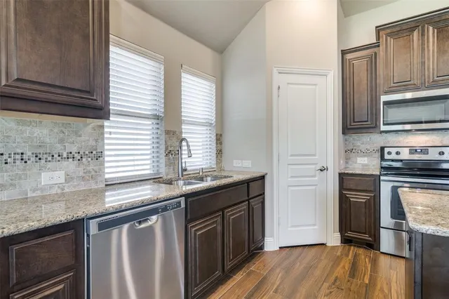 a kitchen with stainless steel appliances granite countertop a stove a sink and a microwave