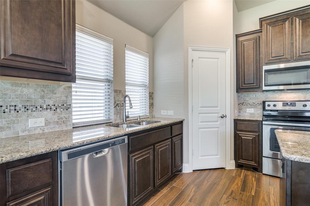 556 Avery Pointe Lavon, TX 75166 - Photo 10 of 32 a kitchen with stainless steel appliances granite countertop a stove a sink and a microwave