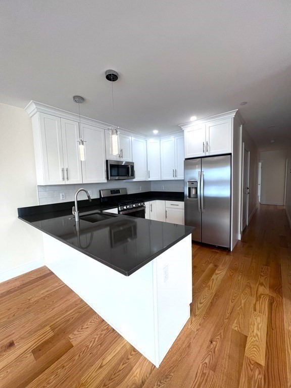 a large kitchen with stainless steel appliances granite countertop a sink a counter space and cabinets