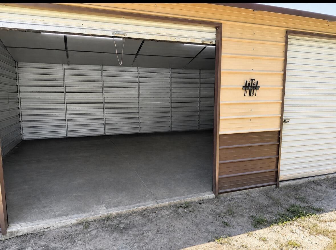 3124 Shaw Road Manning, SC 29102 - Photo 4 of 21 Exterior view of the spacious double-bay metal workshop with both roll-up doors open, offering easy access and plenty of room for vehicles, boats, equipment, or storage.