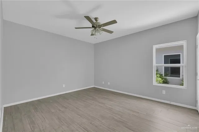 an empty room with a window and ceiling fan