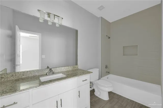 a bathroom with a granite countertop sink a toilet and a mirror