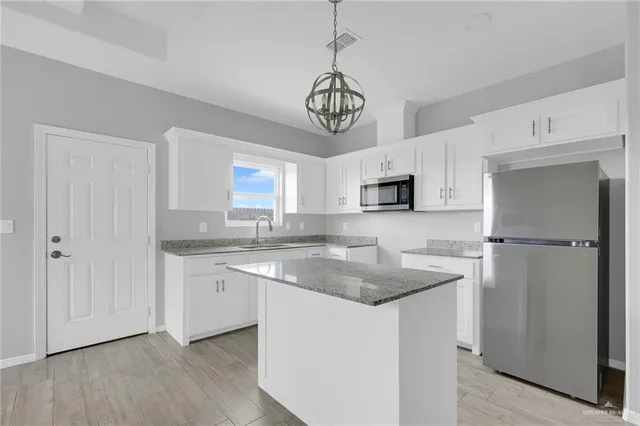 a kitchen with stainless steel appliances granite countertop a sink a refrigerator and a granite counter tops