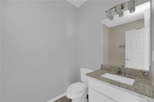 a bathroom with a granite countertop sink a toilet and mirror