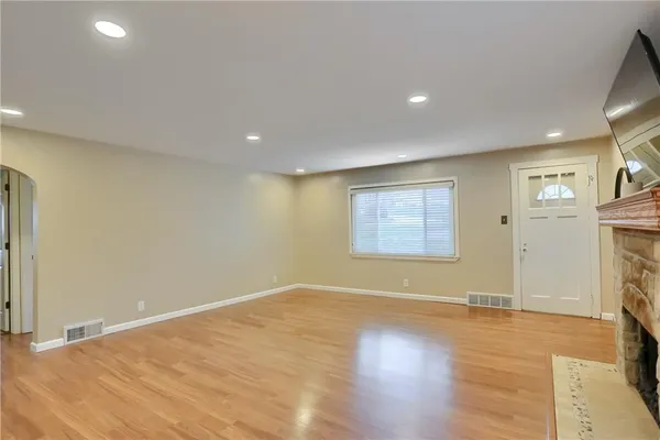 an empty room with a fireplace and wooden floor