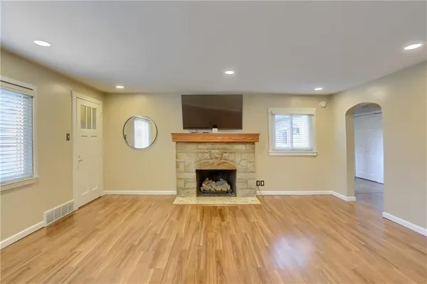 an empty room with wooden floor fireplace and windows