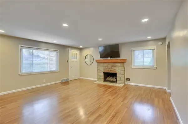 a view of an empty room with wooden floor fireplace and a window