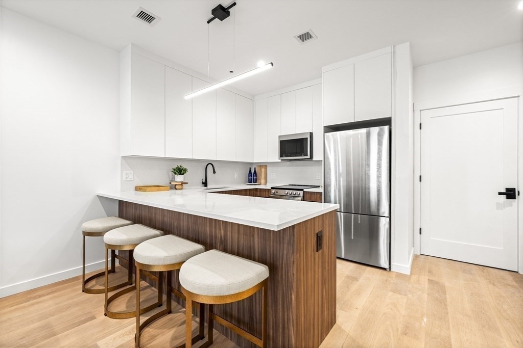 1395 Washington Street, Unit 201 Boston, MA 02118 - Photo 8 of 29 a kitchen with stainless steel appliances a table chairs refrigerator and microwave