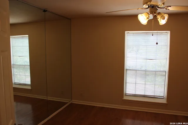 an empty room with windows and fan