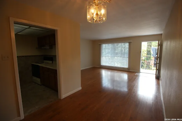 an empty room with wooden floor closet and windows