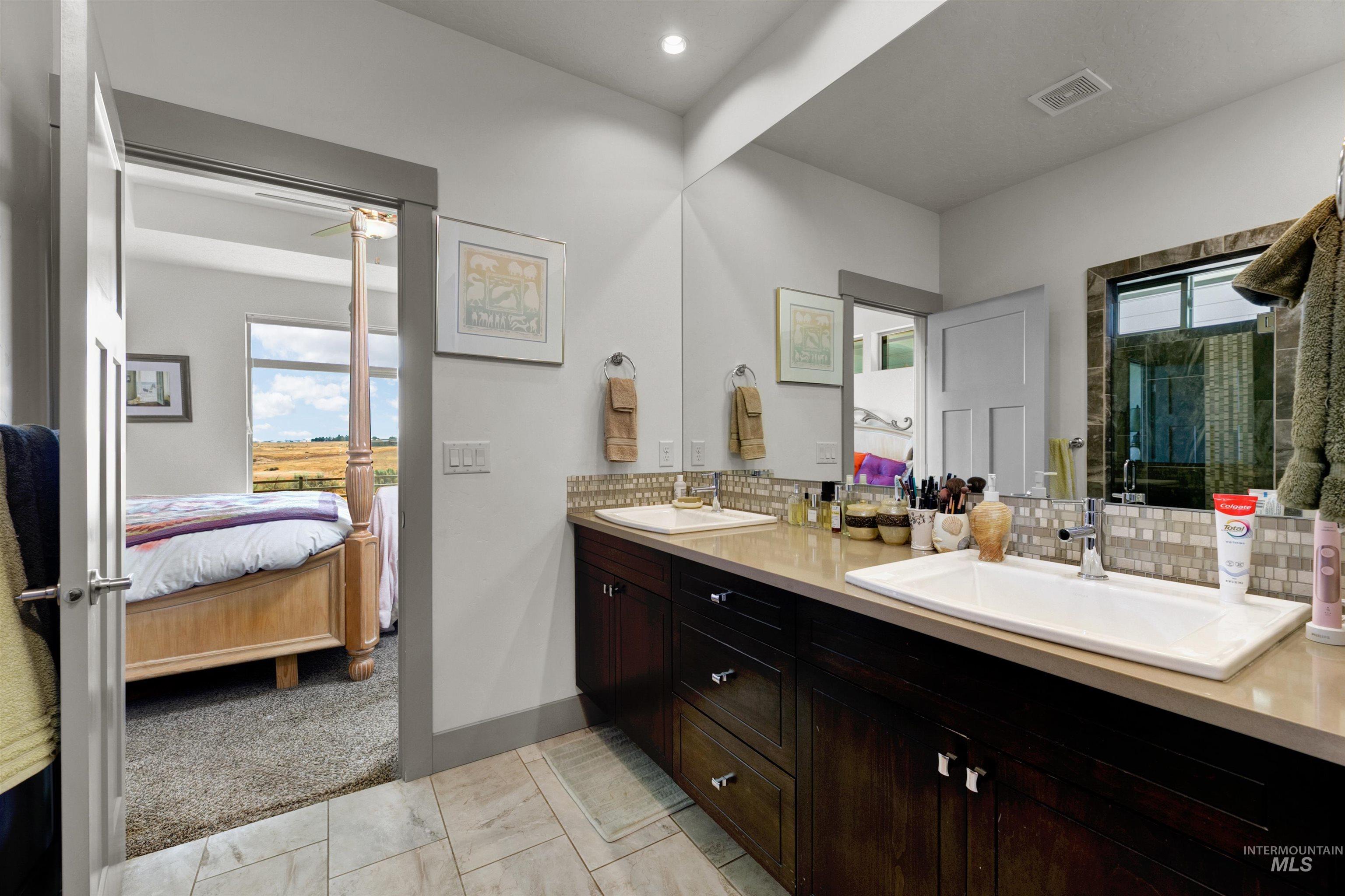 24398 Tombstone Ridge Court Middleton, ID 83644 - Photo 14 of 47 Bathroom featuring a dual vanity with a light-toned countertop, rectangular undermount sinks, and dark wood cabinetry
