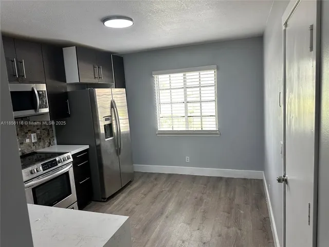 a kitchen with a refrigerator stove and wooden cabinets