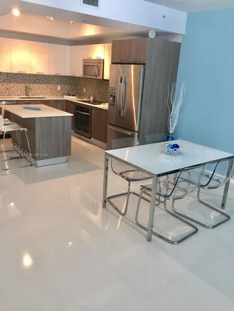 a kitchen with stainless steel appliances granite countertop a table chairs and a refrigerator