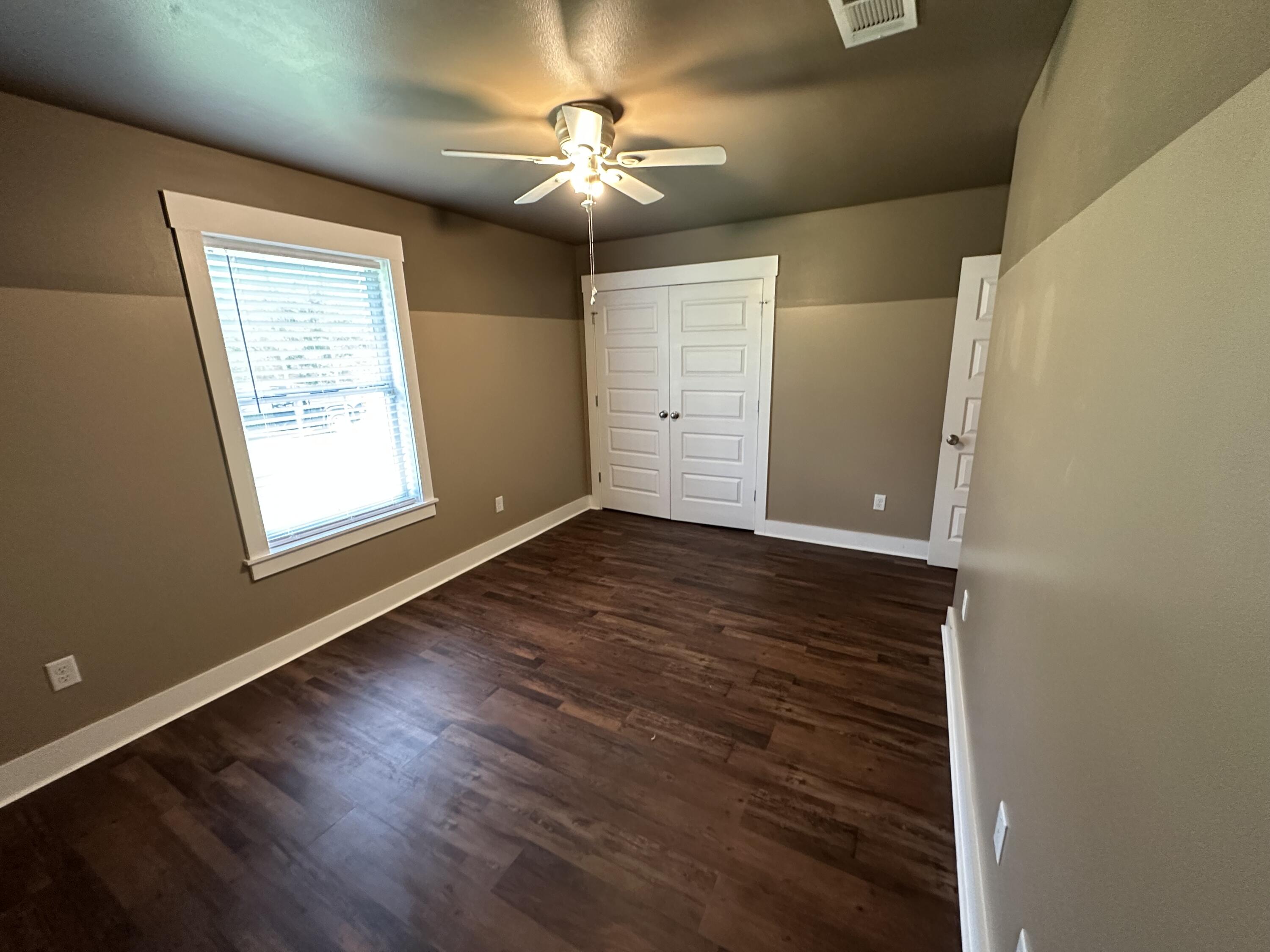 10712 Highway 331 DeFuniak Springs, FL 32433 - Photo 38 of 56 an empty room with wooden floor chandelier fan and windows