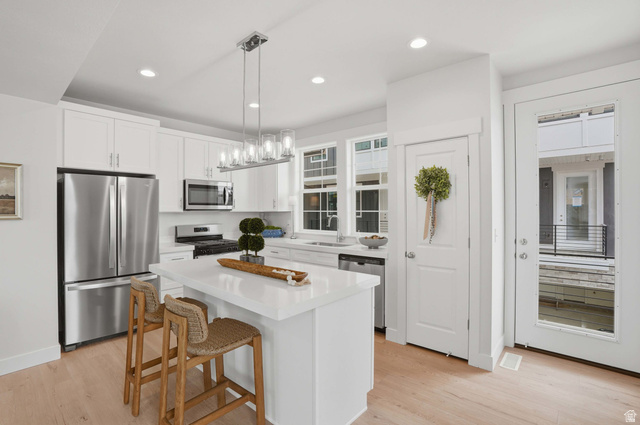 7338 South Seven Tree Lane, Unit 75 Midvale, UT 84047 - Photo 13 of 30 Kitchen featuring stainless steel appliances, white cabinetry, light wood-style flooring, and a center island