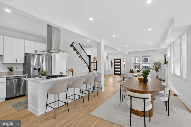 a dining room with stainless steel appliances kitchen island granite countertop a dining table chairs and couches with wooden floor