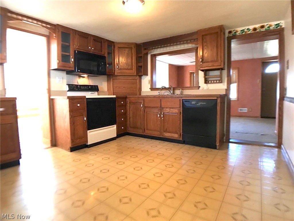 6120 Shaffer Road Northwest Warren, OH 44481 - Photo 4 of 24 12'x 12' eat-in kitchen with newer oak cabinets, vinyl floor, gas range, microwave, and dishwasher, with doorway to family room on left and doorway to combination dining/living room on right.