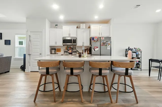 a kitchen with stainless steel appliances kitchen island granite countertop a dining table chairs and granite counter tops