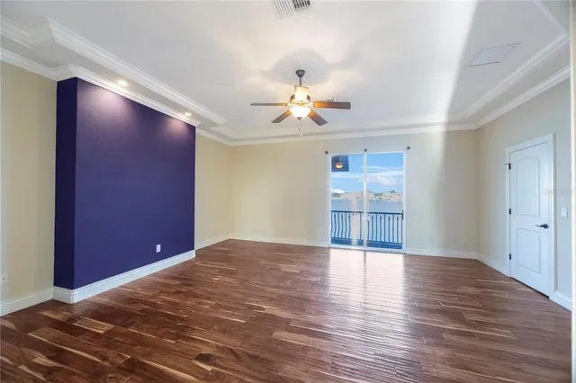 a view of an empty room with a window and wooden floor