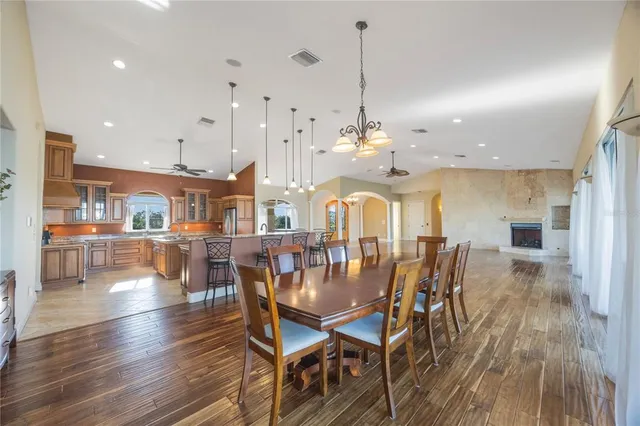 a view of a dining room and livingroom with furniture wooden floor a rug a fireplace and a chandelier