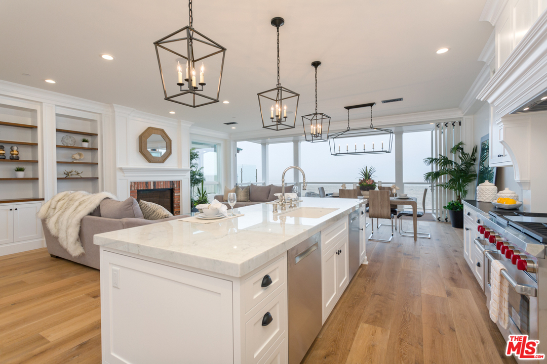 861 Mandalay Beach Road Oxnard, CA 93035 - Photo 9 of 31 a large kitchen with stainless steel appliances kitchen island granite countertop a large stove a sink a dining table and chairs with wooden floor