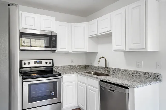 a kitchen with granite countertop cabinets stainless steel appliances and a sink