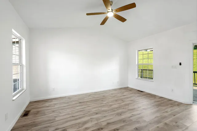 a view of empty room with wooden floor and fan